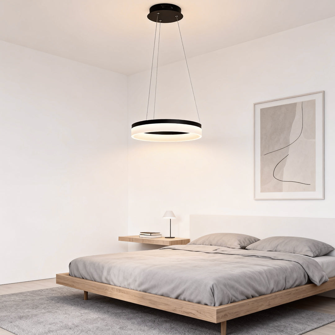 Black ring pendant light used as bedroom ceiling lighting above a low-profile bed.