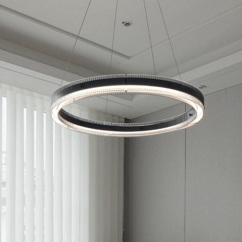 Large black round pendant light suspended in spacious modern interior with concrete walls