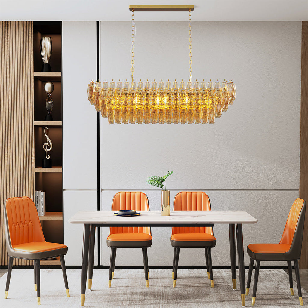 Gold oval glass pendant chandelier glowing warmly above an elegant dining setup.